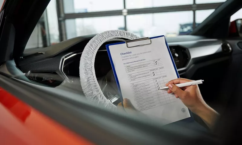Someone sitting in a Volkswagen completing a checklist
