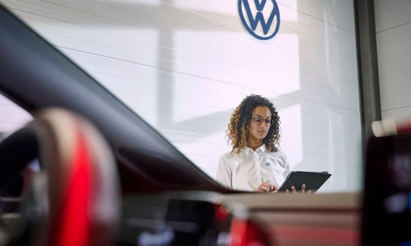 A Volkswagen service employee reviewing a tablet through the windscreen