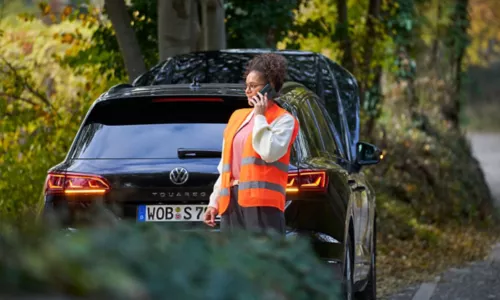 Woman in safety vest calling Volkswagen Roadside Assistance