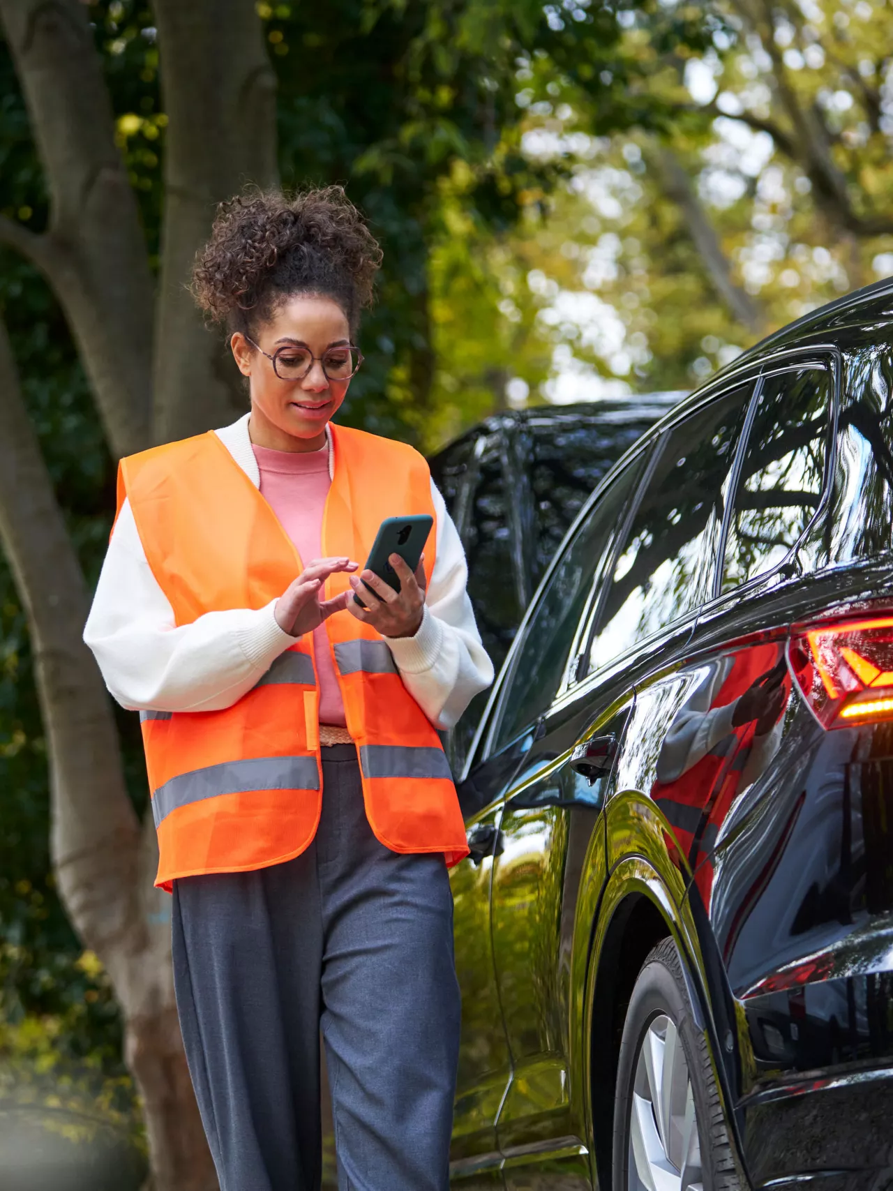 Woman with safety vest and Volkswagen Roadside Assistance employee next to a VW with the bonnet open
