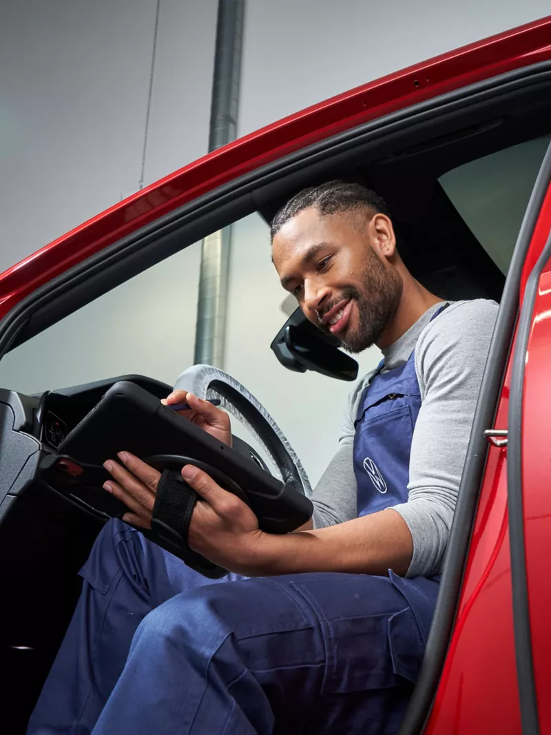 A Volkswagen service employee in a Volkswagen looking at a tablet