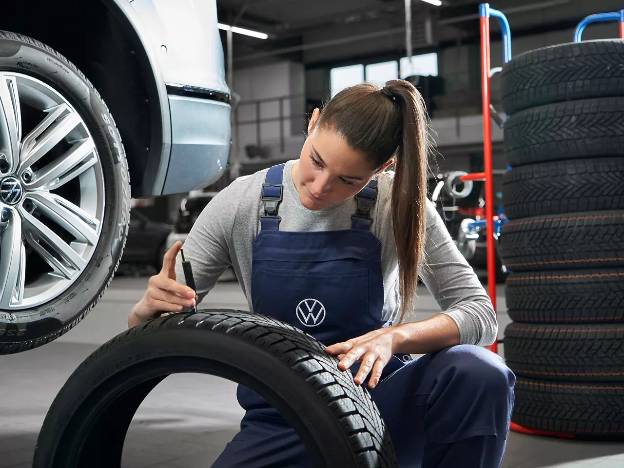 A Volkswagen service technician checking a tyre's tread