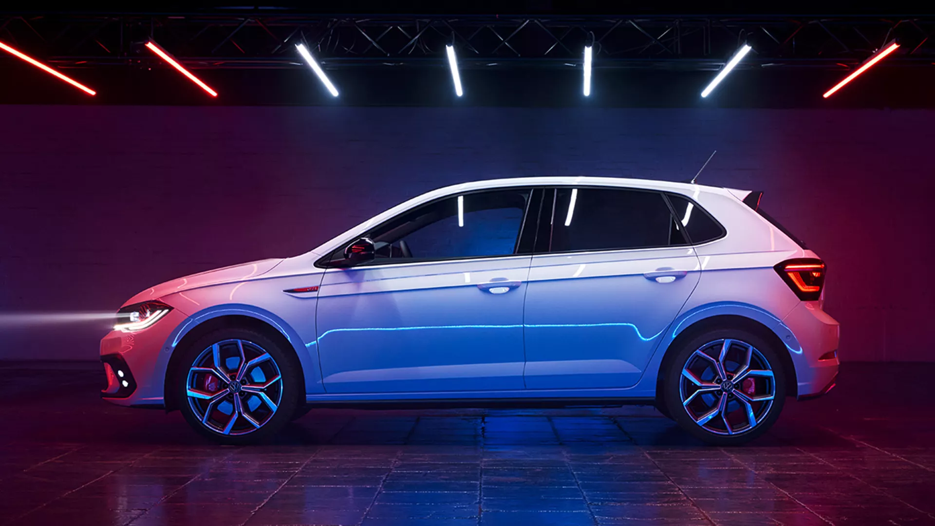 View of the side of a white VW Polo GTI with tinted rear windows, GTI badge on the fender and optional 18-inch "Faro" wheels.
