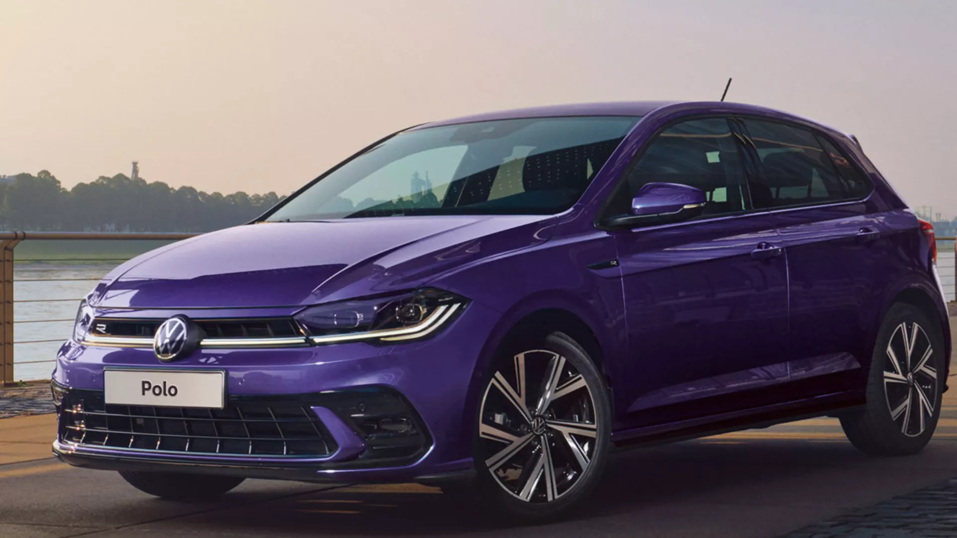 A purple VW Polo with tinted rear windows stands in a parking lot, view from the rear over the side.
