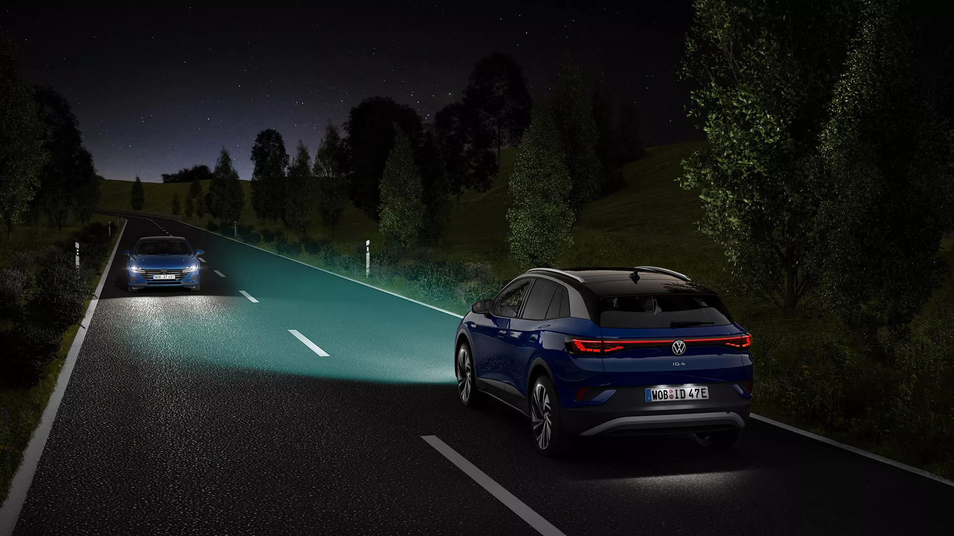 A blue VW ID.4 drives down a street with its lights on at night.