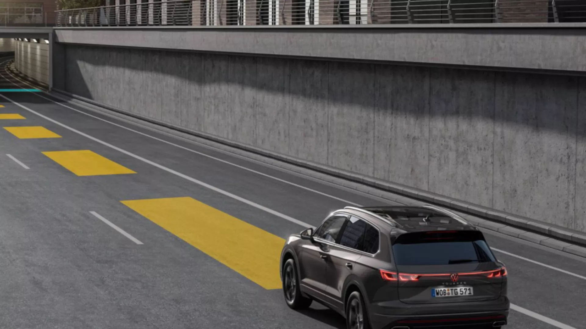 A grey VW Touareg drives on an empty street into a tunnel.
