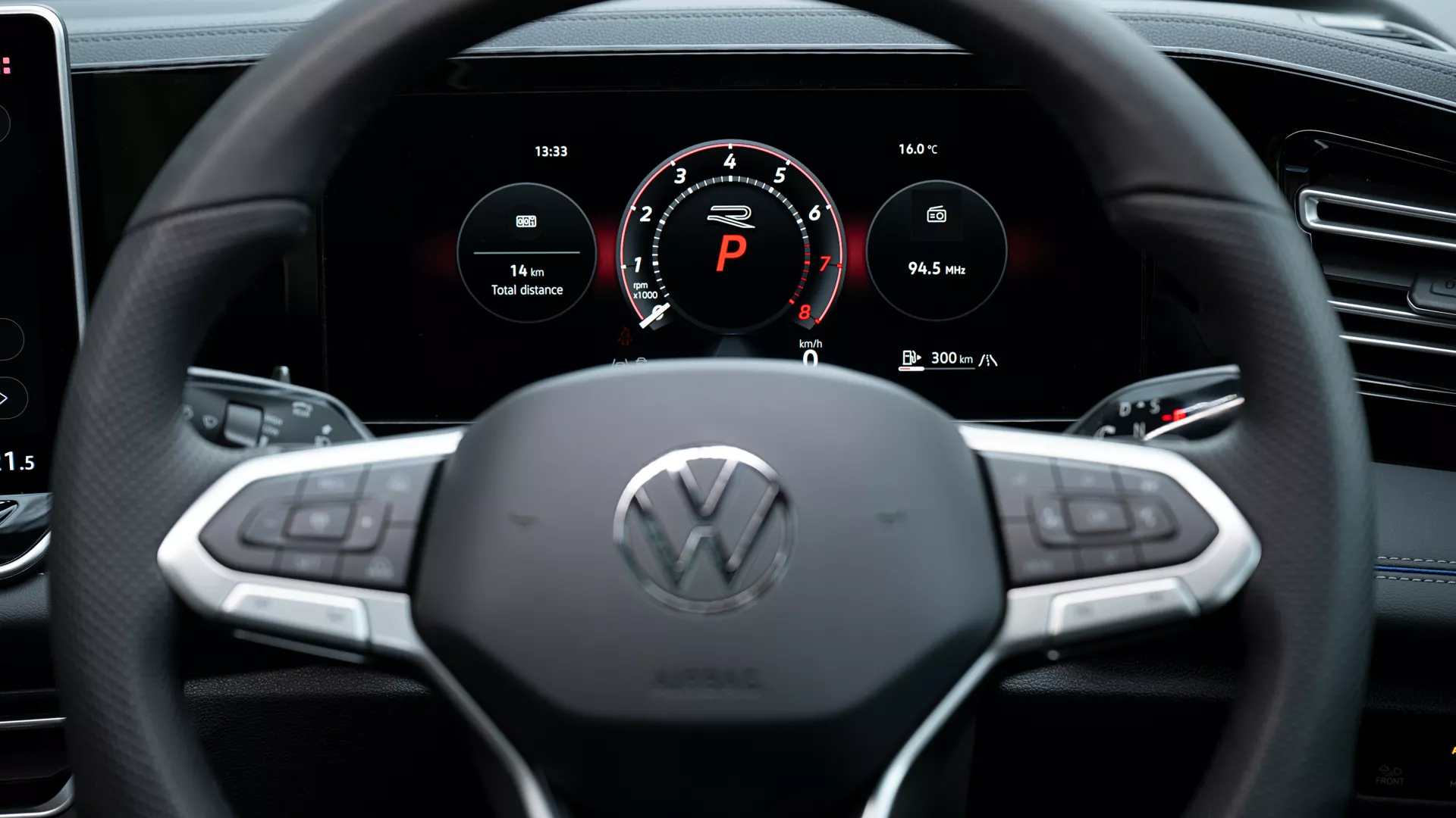 Detailed view of the cockpit in a VW Tiguan. Two hands clasp the steering wheel.